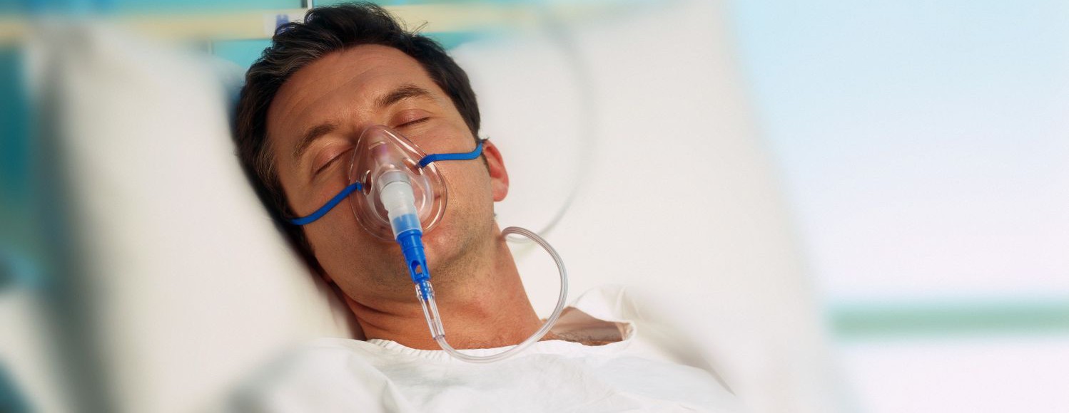 Portrait of a man with an oxygen mask in a hospital bed